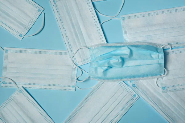 Disposable face masks on light blue background, flat lay. Protective measures during coronavirus quarantine