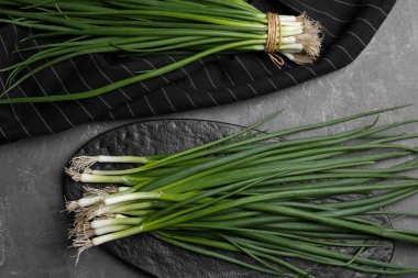 Taze yeşil soğanlar gri masada, düz yatıyordu.