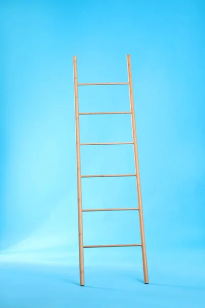 Modern wooden ladder on light blue background