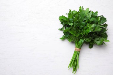 Bunch of fresh green parsley on white wooden table, top view. Space for text clipart