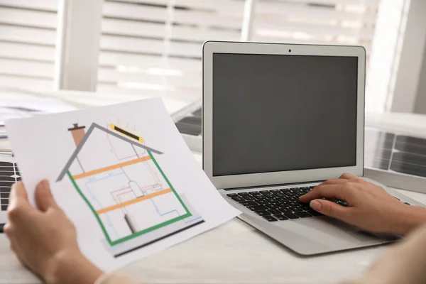 Woman working on house project with solar panels at table in office, closeup