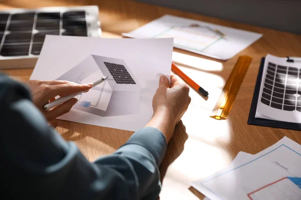 Woman working on house project with solar panels at table in office, closeup