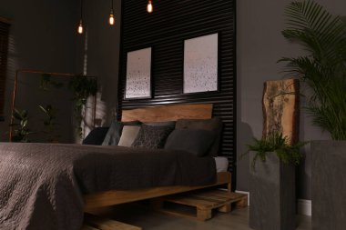 Yeşil bitkiler ve duvarlarında resimler olan rahat bir yatak odası. İç tasarım