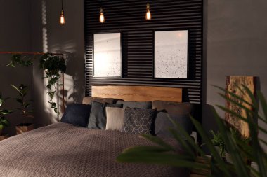 Yeşil bitkiler ve duvarlarında resimler olan rahat bir yatak odası. İç tasarım