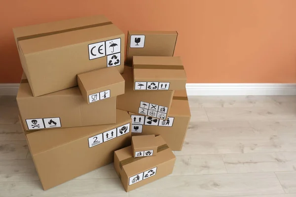 Cajas Cartón Con Diferentes Símbolos Embalaje Suelo Cerca Pared Naranja — Foto de Stock