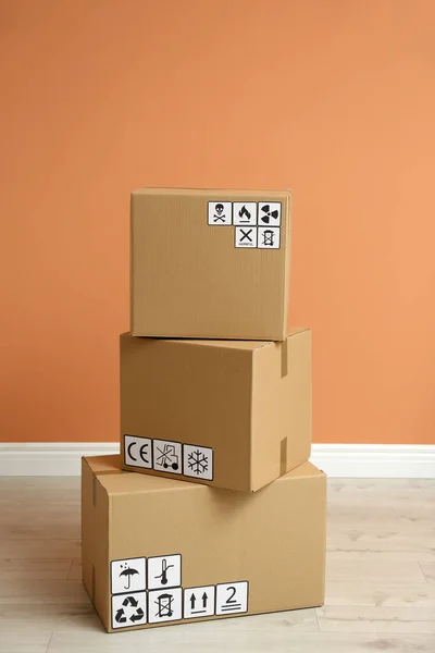 Pappkartonger Med Olika Förpackningssymboler Golvet Nära Orange Vägg Paketleverans — Stockfoto