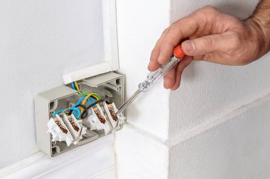 Neon lambalı elektrikçi içeride voltajı kontrol ediyor, yakın plan. 