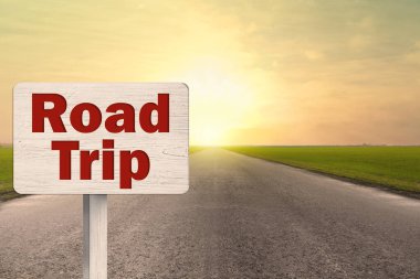 Gün batımında asfalt yolda yazılı tahtadan bir plaket.