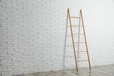 Beyaz tuğla duvarın yanındaki modern ahşap merdiven. Metin için boşluk