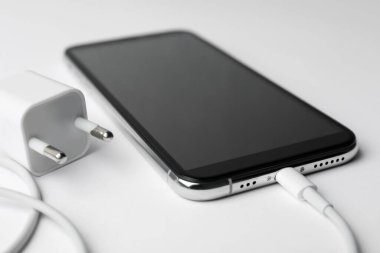 Akıllı telefon ve kabloyu beyaz arkaplanda adaptörle şarj et, kapat