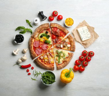 Düz kompozisyonda açık gri masada farklı lezzetli pizzalar vardı.
