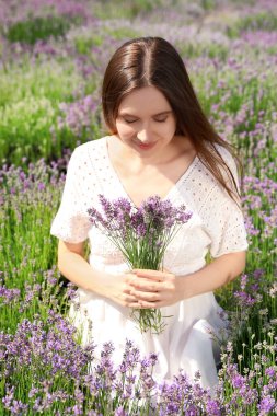 Yaz günü tarlada lavanta buketi olan genç bir kadın.