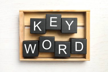 KEYWORD sözcüğüyle siyah küpler beyaz ahşap arka plan, üst görünüm