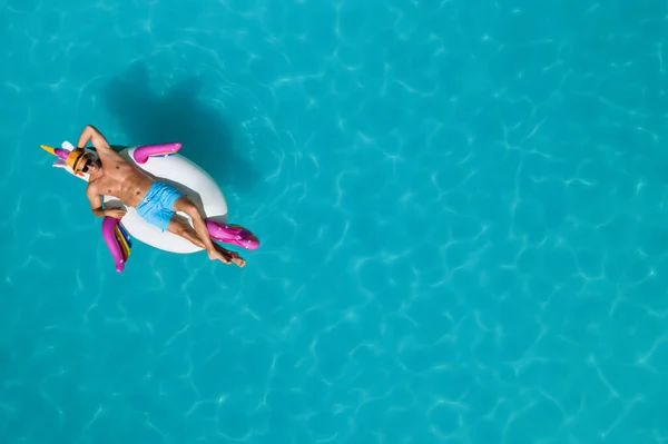 Happy man with inflatable ring in swimming pool, top view and space for text. Summer vacation