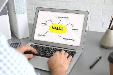 Emlak değeri kavramı. İçerideki masada dizüstü bilgisayarla çalışan adam, yakın plan.