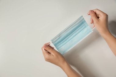 Arka planda tek kullanımlık yüz maskesi tutan bir kadın, mesaj için yeri olan bir kadın. Koronavirüs karantinası sırasında koruyucu tedbirler
