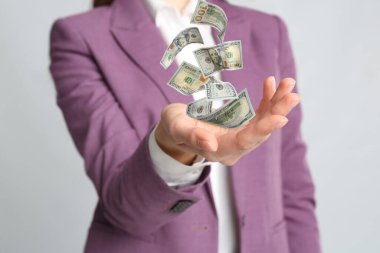 Açık gri arka planda parası olan bir kadın, yakın plan. Para birimi değişimi