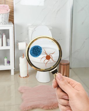 Elinde büyüteç olan bir kadın tuvaletteki mikropları algılıyor.  