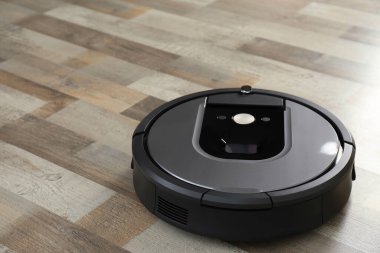 Ahşap zeminde modern robot süpürge.