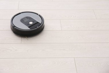 Ahşap zeminde modern robot elektrikli süpürge. Metin için boşluk