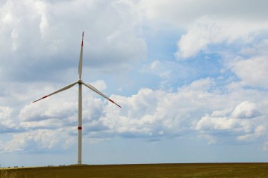 Bulutlu bir günde modern rüzgar türbini sahada. Alternatif enerji kaynağı