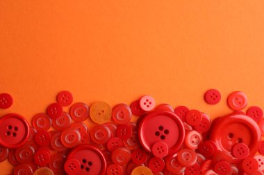 Turuncu arka planda bir sürü kırmızı dikiş düğmesi var. Metin için boşluk