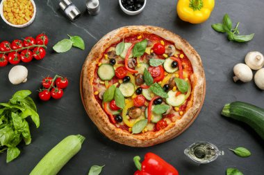 Siyah masada nefis sebzeli pizzayla yassı bir kompozisyon.