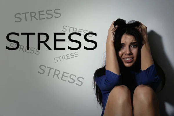 在白墙附近沮丧的年轻女子和单词Stress — 图库照片