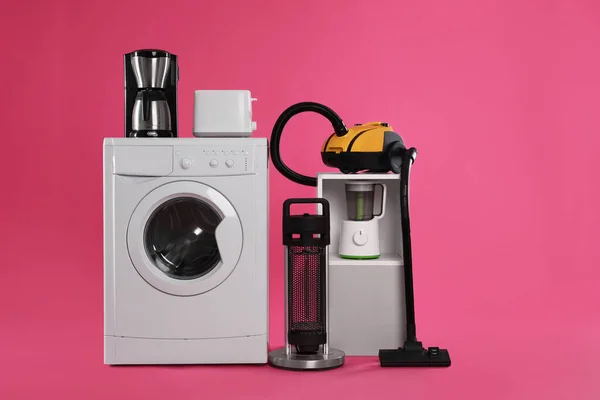 ピンクの背景に掃除機付きの異なる家電製品のセット — ストック写真
