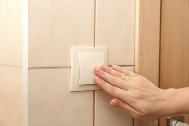Kadın evin içinde düğmeye basıyor, elini kapatıyor.