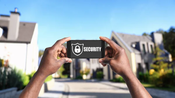 Alarm system. African American man using phone outdoors, closeup