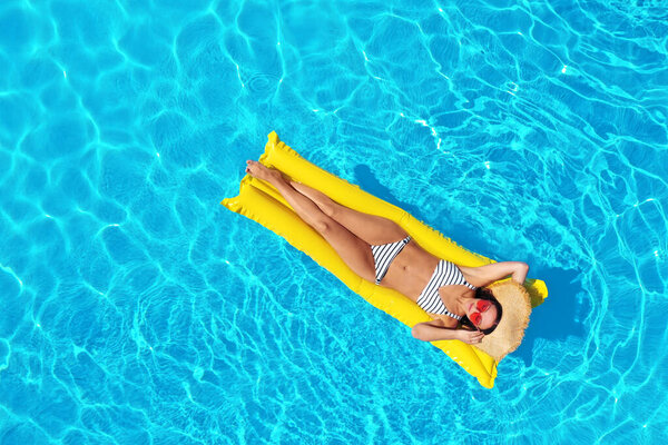 Молодая женщина с надувным матрасом в бассейне, вид сверху