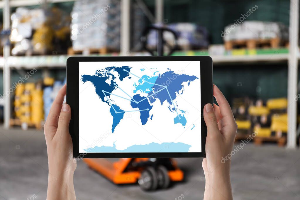 Wholesale trading. Woman tablet with world map illustration at warehouse, closeup 