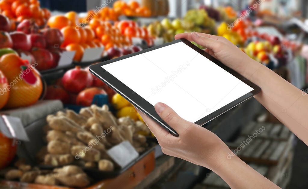 Wholesale trading. Woman using WMS app on tablet at market, closeup 