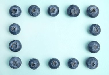 Açık mavi arka planda taze olgun yaban mersini çerçevesi, düz. Metin için boşluk