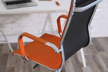 Ofis sandalyesi ve ahşap masası olan rahat bir iş yeri, yakın plan.