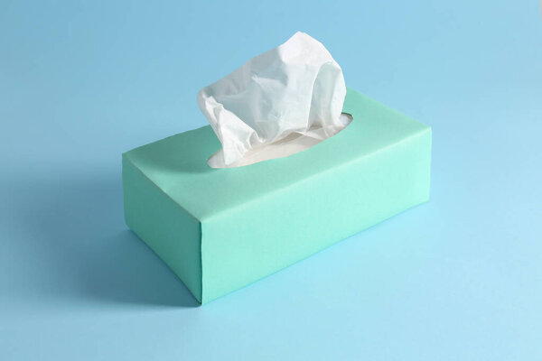 Box of paper tissues on light blue background