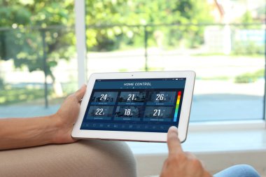 Enerji verimliliği ev kontrol sistemi. Farklı odalarda ısıyı ayarlamak için tablet kullanan adam, yakın plan