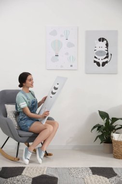 İçerde oturan resimli bir dekoratör. Çocuk odası iç tasarımı.