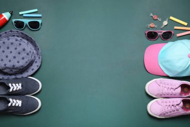 Yeşil karatahtanın üzerinde ayakkabılı, şapkalı ve çocuk aksesuarlı düz kompozisyon, yazı için boşluk. Okul tatili