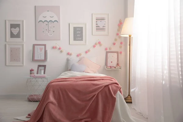 Stylish child\'s room interior with beautiful pictures and comfortable bed