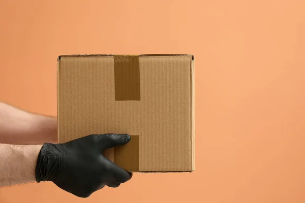 Kurir Håller Kartong Orange Bakgrund Närbild Paketleverans — Stockfoto