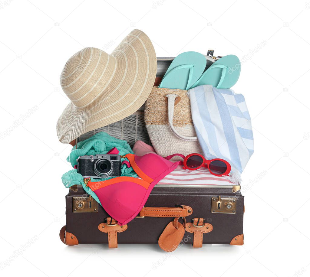 Open vintage suitcase with different beach objects packed for summer vacation isolated on white