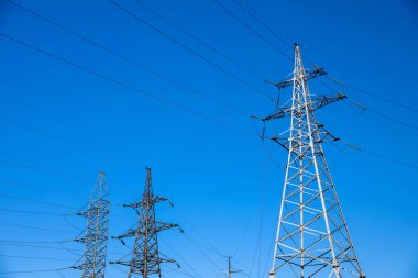 Mavi gökyüzüne karşı modern yüksek voltaj kuleleri