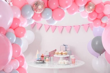 Kız için bebek partisi. Odadaki lezzetli ikramlar balonlarla süslenmiş.