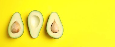 Taze olgun avokadoları kes ve sarı arka plandaki yazı için yer aç, düz yat. Pankart tasarımı