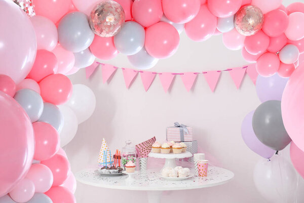 Baby shower party for girl. Tasty treats on table in room decorated with balloons