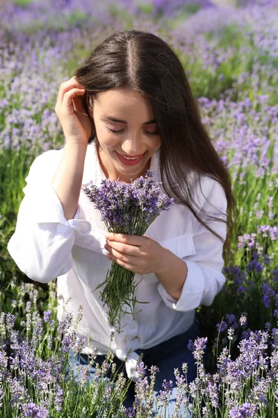 Young woman with lavender bouquet in field on summer day