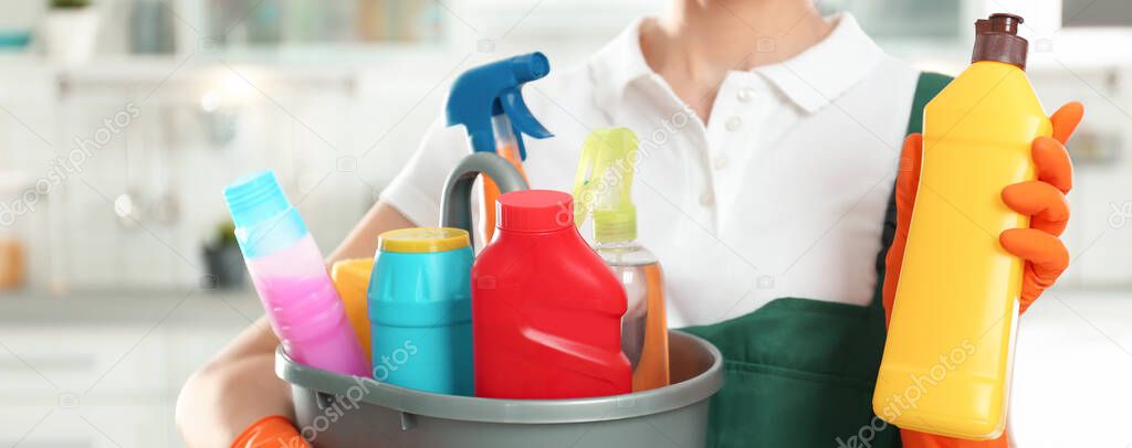 Closeup view of woman with detergents and bottle in kitchen, banner design. Cleaning service