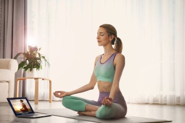 Koronavirüs salgını sırasında yoga kursu. Evde dizüstü bilgisayarla eğitmenlik yapan bir kadın.